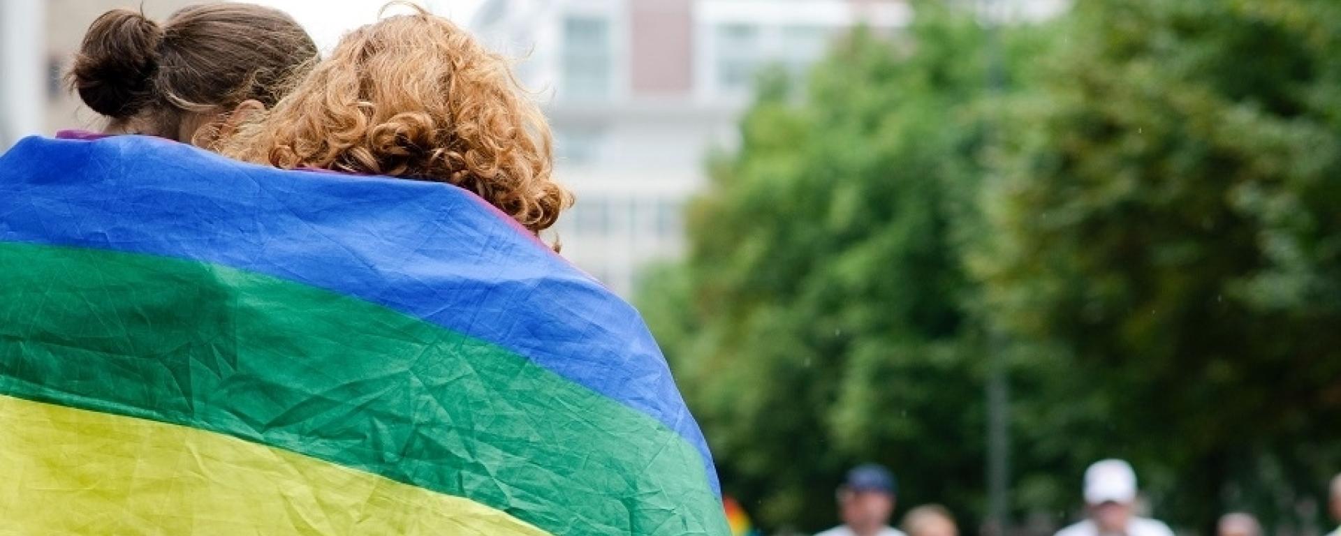 Ein Paar mit Regrenbogenbflagge um (© Stadt Frankfurt)