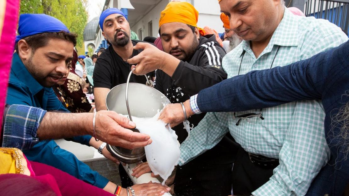 Mehrere Sikh-Gläubige bei einer Erntedankfest-Zeremonie, bei dem sie den Mast reinigen, der die Flaggge ihrer Religionsgemeinschaft trägt.