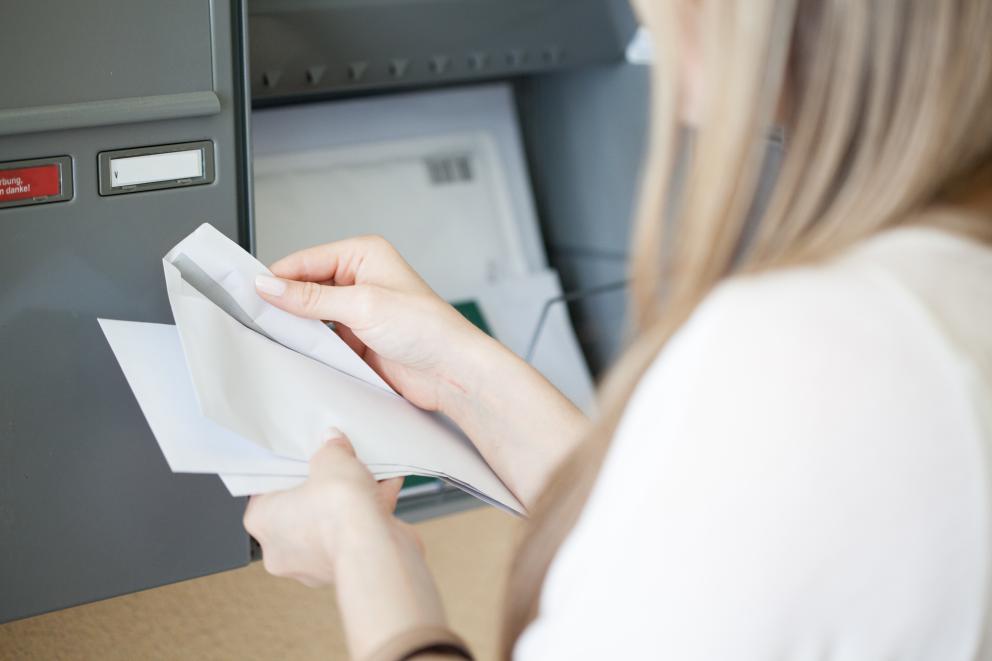Einer Frau öffnet Post an ihrem Briefkasten
