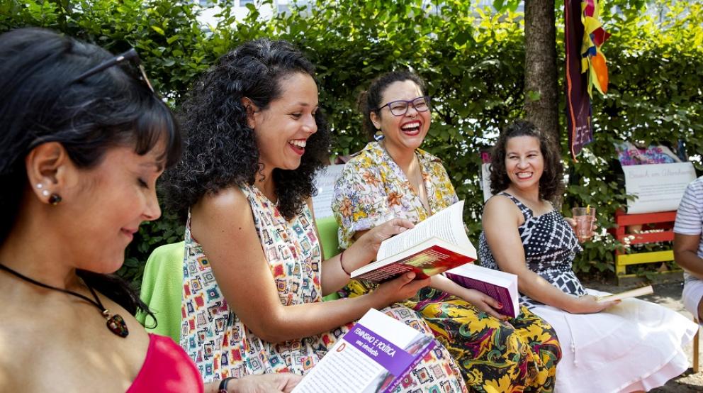 Mehrere Frauen unterhalten sich lachend mit Buch dabei